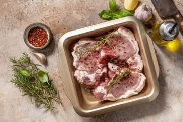 Fresh raw pork loin on the bone with spices and marinade on a stone tabletop, preparation for baking or barbecue. Top view flat lay background.