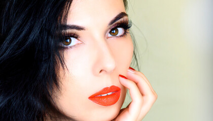 Beautiful female face. Beautiful makeup and bright red lips. Female fingers with red manicure touch the face.