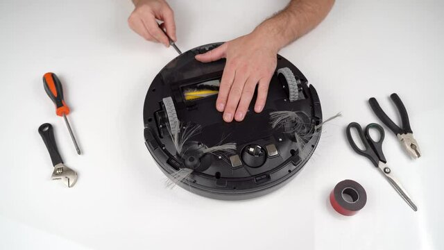 Worker Repairing Wheels of Robot Vacuum Cleaner