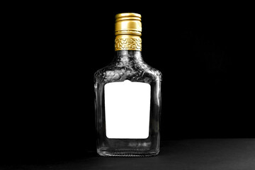Mockup label on empty glass bottle of whiskey, cognac or vodka on a black background. Template, copy space photo