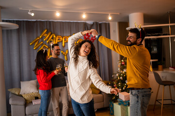 Loving couple enjoying Christmas celebration at home with friends 