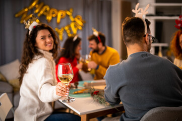 Happy friends toasting at Christmas dinner at home.