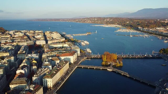 Aerial drone footage of the Rhone river that flow through Geneva city center with the Rousseau island by lake Geneva in Switzerland. Shot with a rotation motion