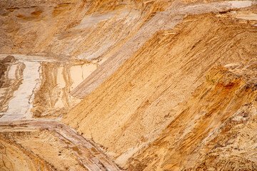 Textural sand, with  relief surface, multi-colored layers and different in size of granules, in outdoor sand career, after mining ore and sand for construction.
