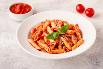 Classic italian pasta penne alla arrabiata with fresh basil on a light background