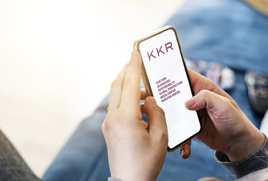 Young woman using her mobile phone with the application of the American investment company KKR