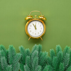 Golden alarm clock and decorative fir branch border on green-olive paper background. Creative...
