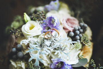 Obraz na płótnie Canvas Beautiful toned picture with wedding rings against the background of a bouquet of flowers