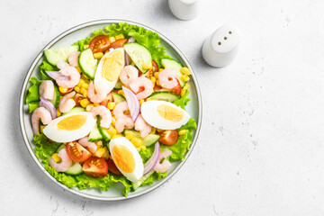 Egg shrimp vegetable salad on plate on light background. Top view, copy space.