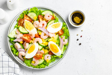 Summer colourful shrimp egg vegetable salad on plate on light background. Top view, copy space.
