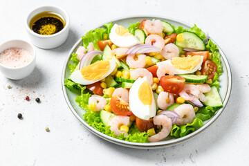 Shrimp egg cucumber tomato salad on plate on light background. Top view, copy space.
