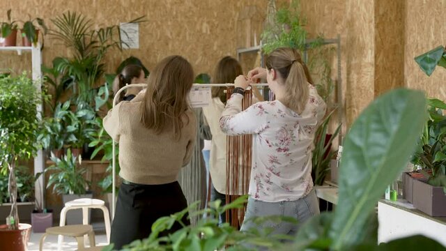 Group of women attending art class. Female students and teacher makes home decor in Boho style in workshop together. Weaves handmade macrame at art school studio. Creativity, people education