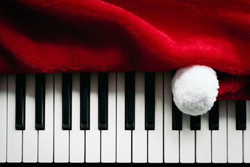 Christmas music background. Santa Claus hat and piano keys, keyboard. Playful red white black Christmas.