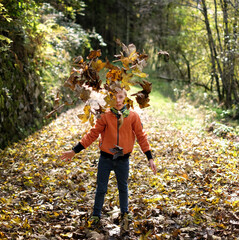 Boy play with the autunm leaves on a dolomites path