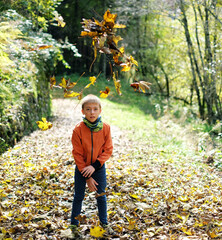 Boy play with the autunm leaves on a dolomites path