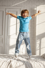 happy child boy having fun jumps and plays bed at home