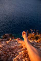 woman legs at the cliff on sunset