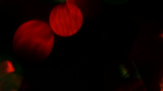 Multicolored light leaks on a black background with bokeh effect for video stylization, transitions. Flashing bokeh of Christmas. Abstract background