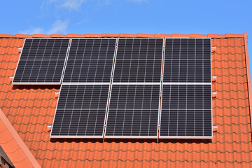 Solar panels on the house roof and against the wall wall on a sunny day. Summer.