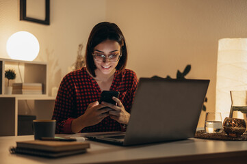 Beautiful woman using smartphone and a laptop while working from home