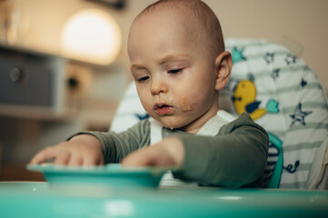 Obraz premium Adorable little baby eating his dinner and making a mess