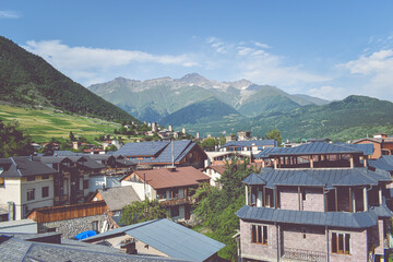 Fototapeta na wymiar Beautiful highland townlet Mestia in the Svaneti region, Georgia, Asia. Cityscape view of traditional rural houses with green hills, famous towers and mountains in the background