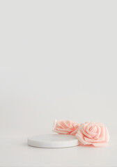 White marble podium on the white background with pink flowers. Podium for product, cosmetic presentation. Creative mock up. Pedestal or platform for beauty products.