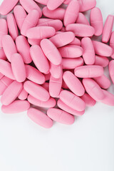 Obraz na płótnie Canvas Pink vitamin pills for women on a white background.