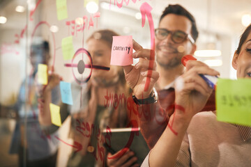 Close-up of creative business team makes mind map on glass wall at casual office.