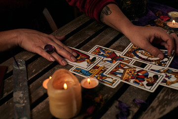 Pythoness reads tarot cards on a table with candles