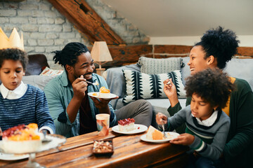Cheerful black family has fun while eating Birthday cake at home.
