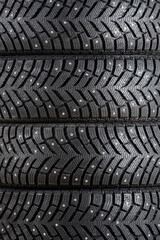 New winter car tires with spikes close-up vertically. Texture, background