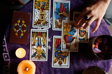 Close-up of a fortune teller reading tarot cards on a table with purple tablecloth