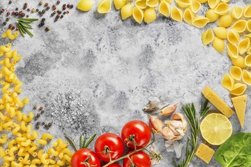 spaghetti pasta, red tomatoes, garlic and herbs on a table on a dark background