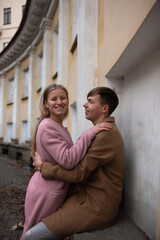 a couple in love a guy and a girl are walking in the parks of a beautiful city in autumn in November with a friend of a white fluffy big dog