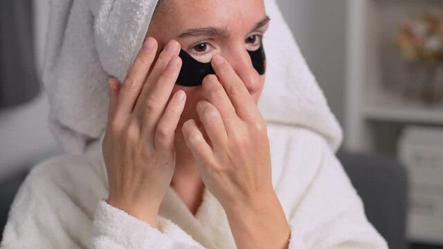 A woman takes care of the skin of her face, she uses patches to smooth the nasolacrimal groove