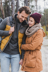 Fototapeta premium young woman hugging boyfriend while walking in autumn forest