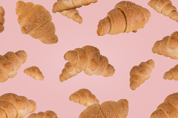 Freshly baked croissants flying in the air isolated on a bright pink background.