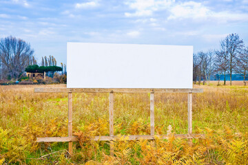 A blank wooden advertising billboard immersed in a field