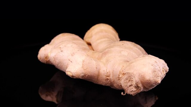 Ginger root on a black background. Fresh and organic ginger rotating on a black background