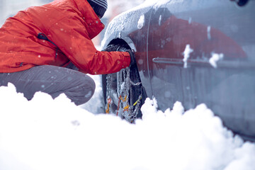  man putting winter chains on car.Confused man does not know how to put snow chains on car tire. - Powered by Adobe