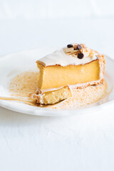French flan on white plate with biscuit crumbs around, with almonds on top. Piece of cake on white bright background, traditional french  dessert