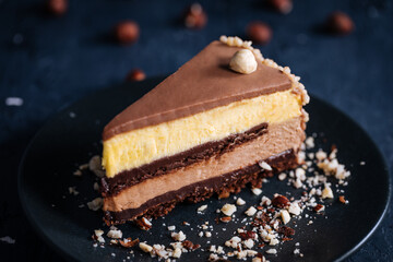 Nougat vanilla and chocolate glazed cake in four layers with hazelnuts on top and hazelnut crumbs...