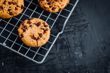 Chocolate chip cookies with tea in background in a dark moody atmosphere 