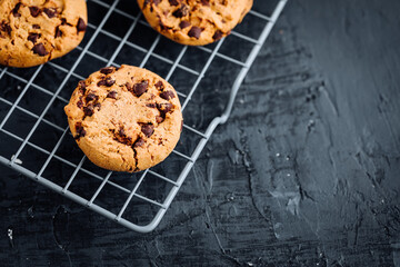 Chocolate chip cookies with tea in background in a dark moody atmosphere 