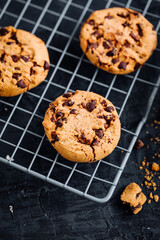 Chocolate chip cookies with tea in background in a dark moody atmosphere 