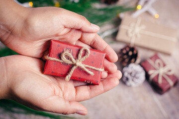 Woman holds a christmas gift in the palm of her hands to deliver it