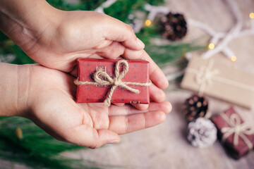 Woman holds a christmas gift in the palm of her hands to deliver it