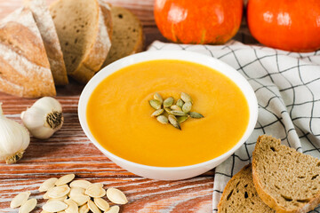 Pumpkin cream soup and rye bread on a wooden background. Delicious and healthy food. Close-up.