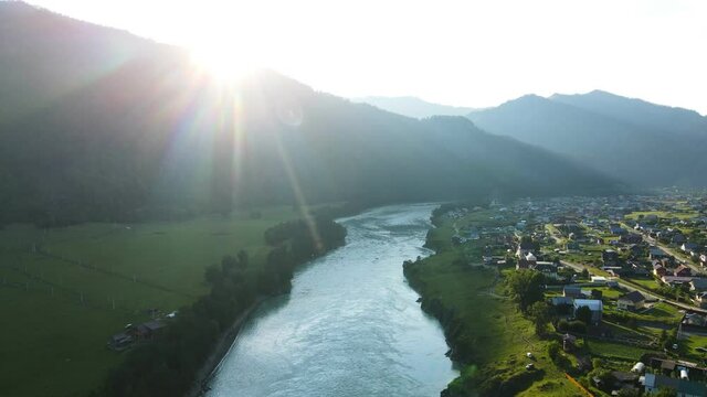 A small town against the backdrop of a mountain landscape and a counter sun